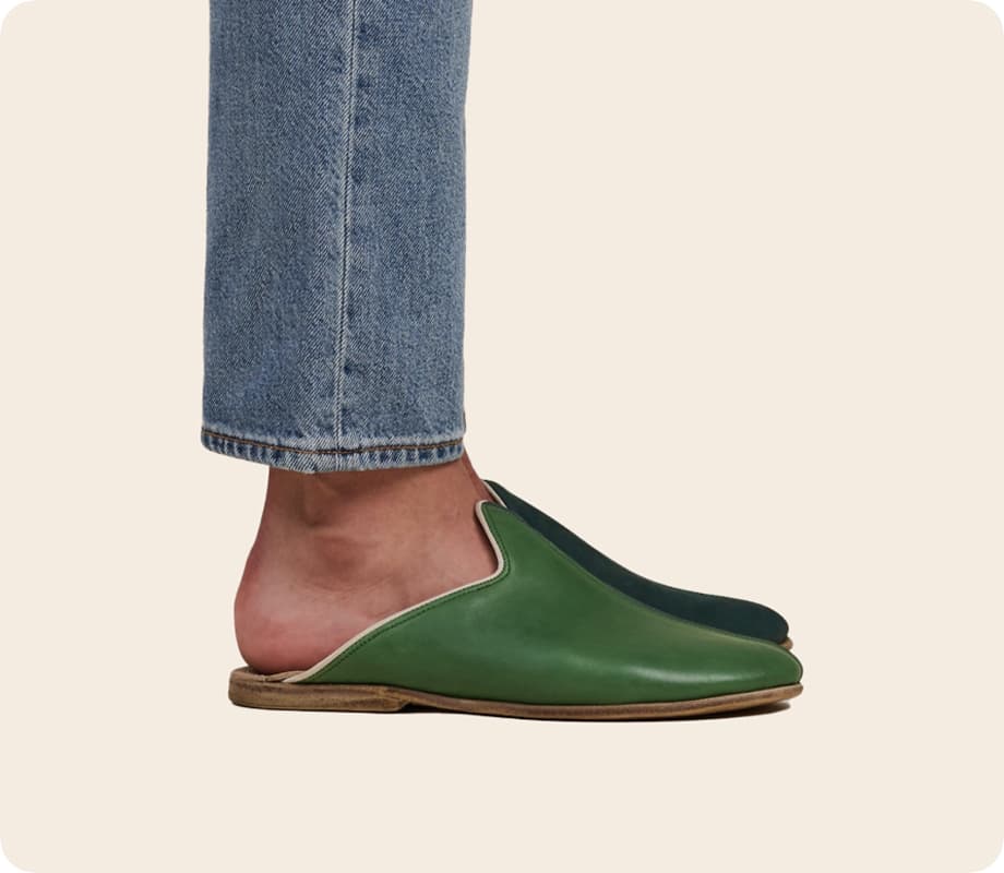 Green leather mule photographed on a model wearing denim.